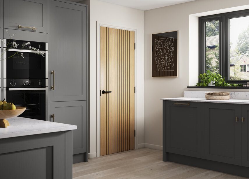 Modern kitchen with gray cabinets, marble countertops, and a wooden door.