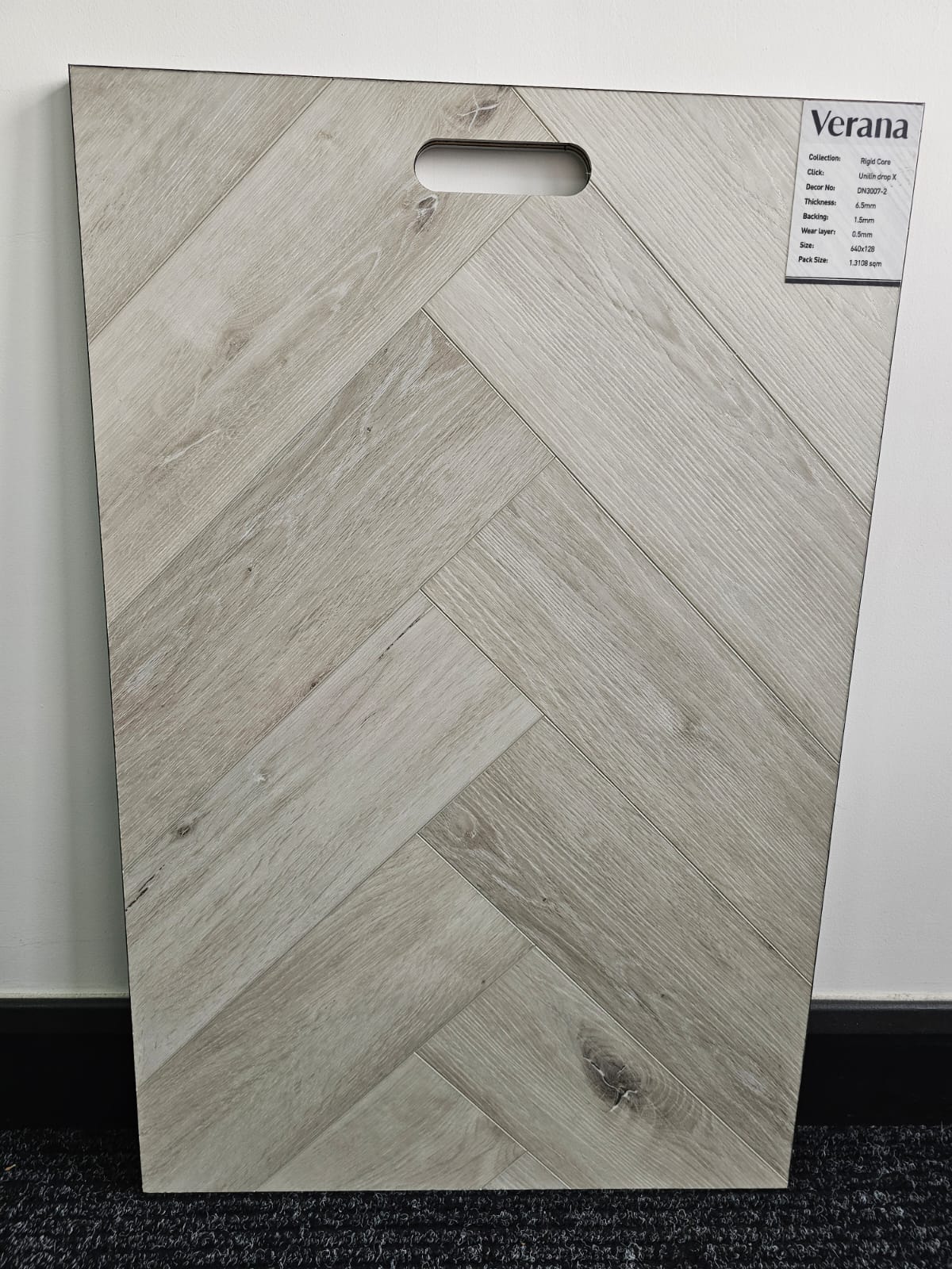 Plank flooring sample with herringbone pattern and 'Verana' branding on a white background