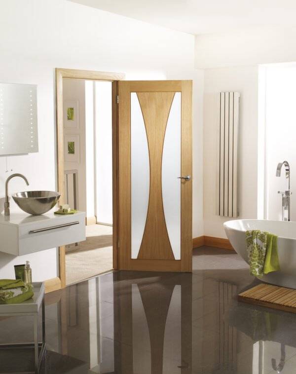 Bathroom interior with a wooden door featuring glass panels.