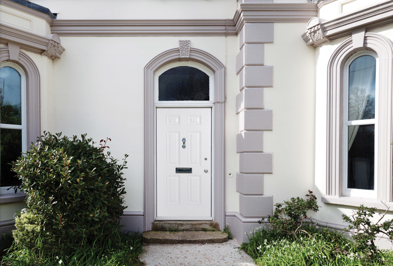 White front door of a house with decorative architecture and greenery.