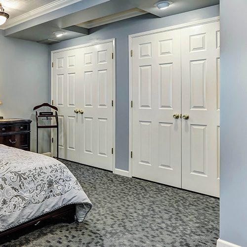 Bedroom with white closet doors and a bed with patterned bedding.