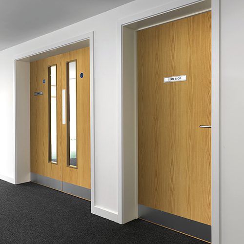 Wooden doors with glass panels and a 'Staff Room' sign in an office setting.