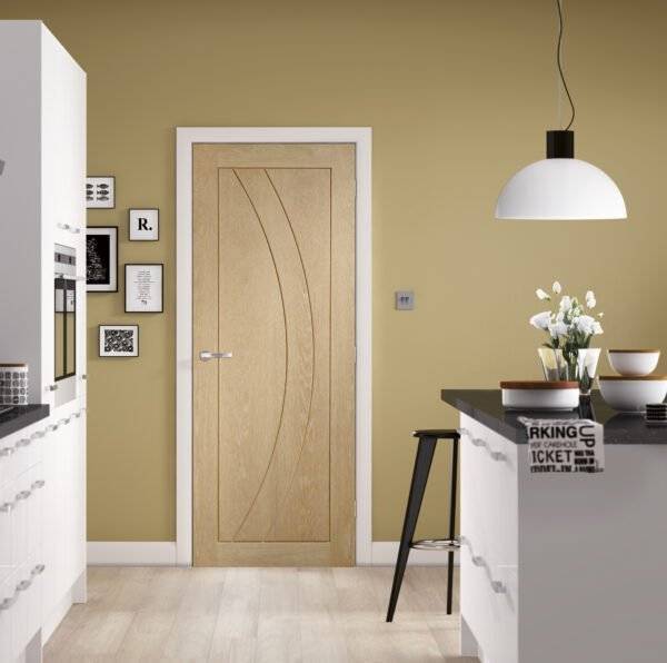 Modern kitchen interior with a wooden door and light-colored walls.