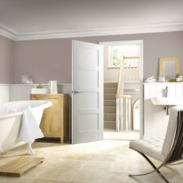 Modern bathroom interior with a freestanding bathtub, wooden cabinet, and white door.