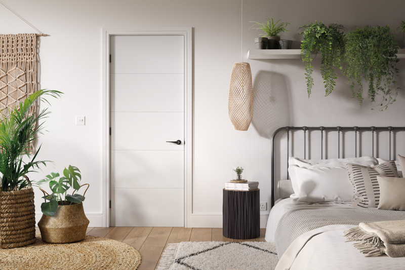 Modern bedroom with a bed, plants, and a white door.