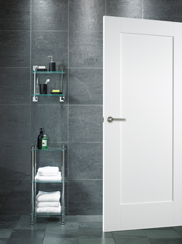 Bathroom with glass shelves against a tiled wall and a white door.