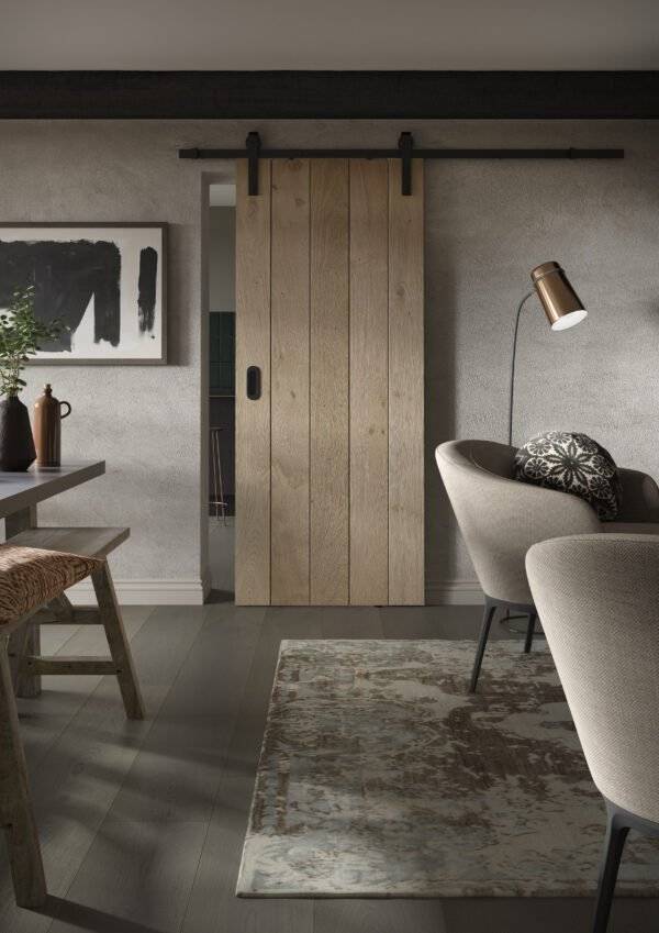 Modern interior with wooden sliding door, gray chairs, and abstract art on a wall.