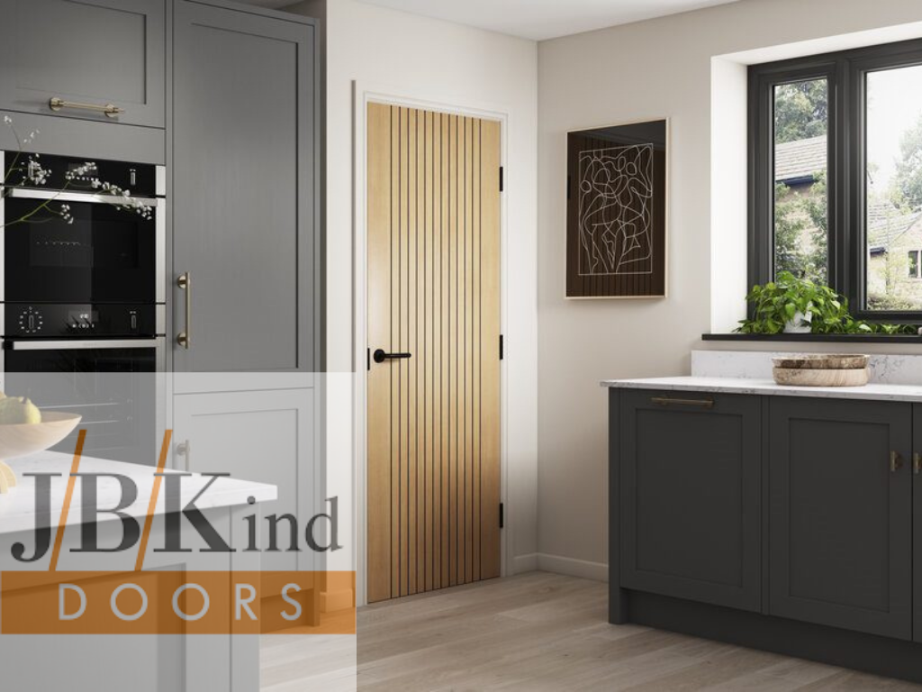 Modern kitchen with gray cabinets, a wooden door, and JB Kind Doors branding.