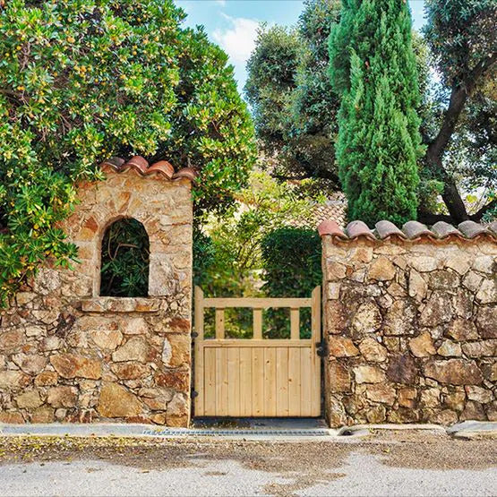 Stone wall with a wooden gate and greenery